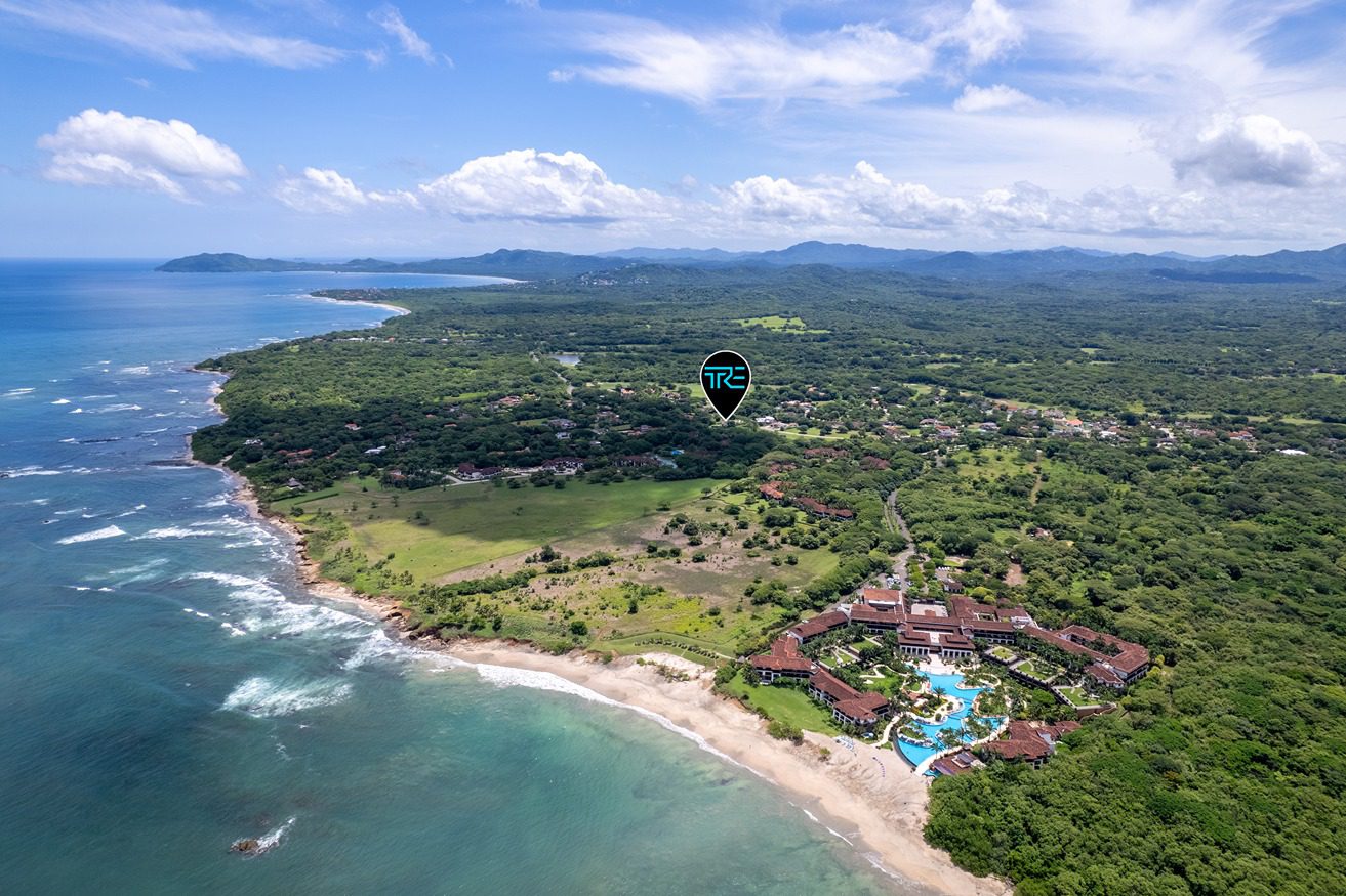 Aerial view of the Hacienda Pinilla coastline, with surf breaking along a wooded shore